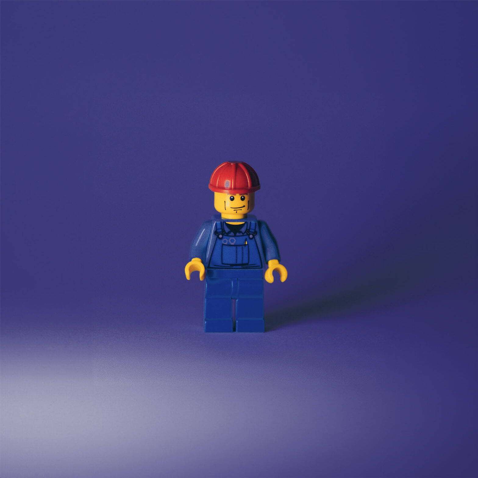 Lego man dressed as a contractor, wearing a hard hat and coveralls.