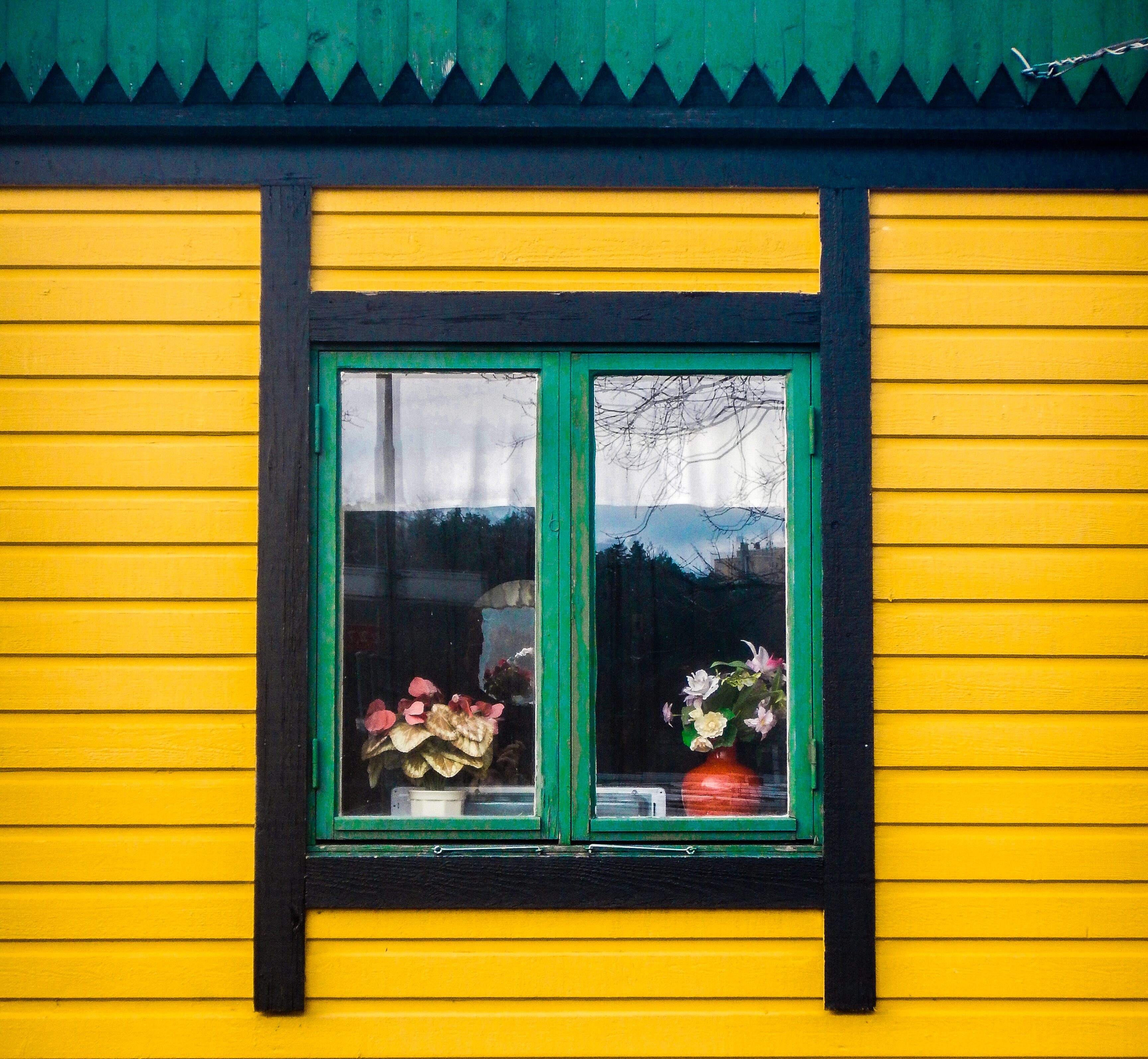 Yellow house with green roof and window.