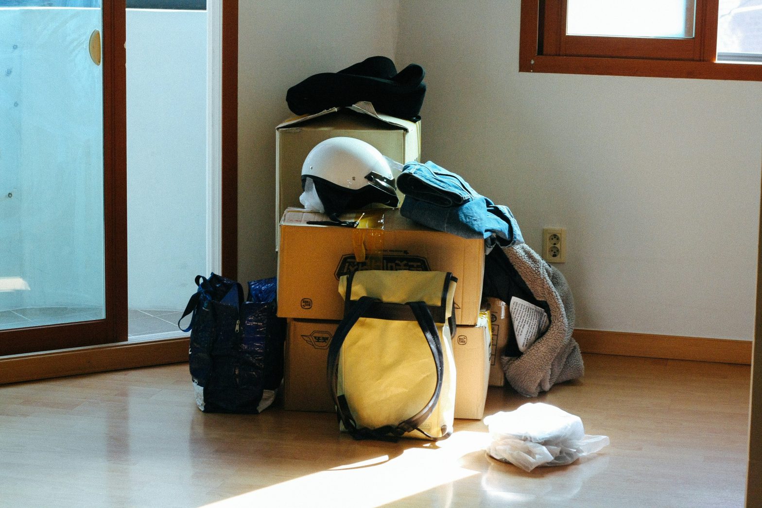 Cardboard boxes and personal belongings stacked in an empty room
